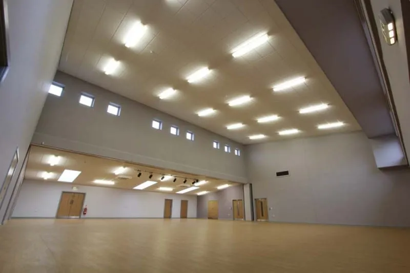 The empty main hall: a large open room with a pale wood floor, high ceiling and rows of ceiling lights.